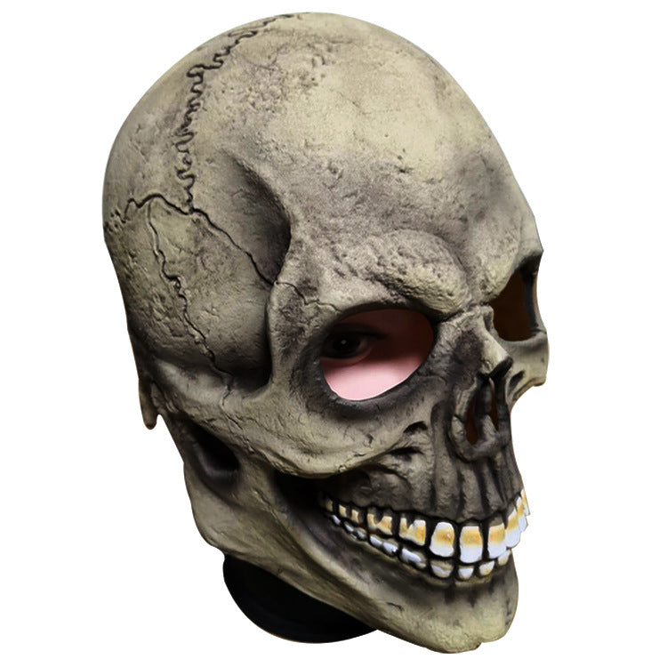 Realistic skull mask with detailed cracks and shadows, revealing human eyes through the eye sockets. The teeth are prominently displayed, accentuating a spooky appearance.