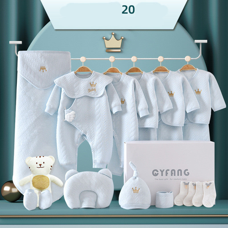 Baby clothing set includes a sleeping bag, jumpsuit, three coordinated outfits, hat, socks, pillow, and a teddy bear in light blue, with gold crown accents, displayed neatly.