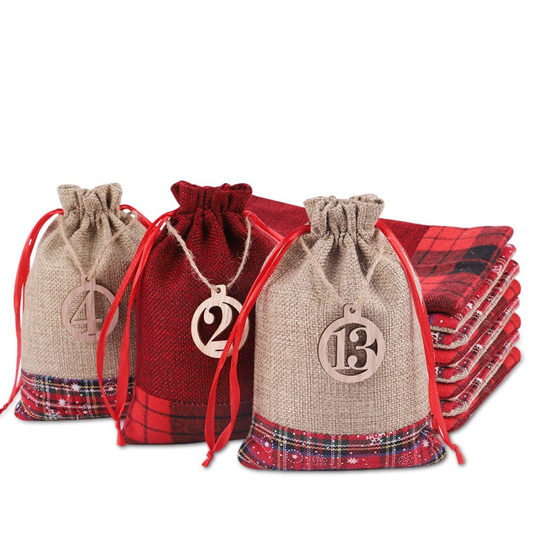 Three drawstring bags with red plaid trim, labeled 4, 2, and 13, featuring red ties and wooden numbers, stand in front of stacked red plaid cloths.