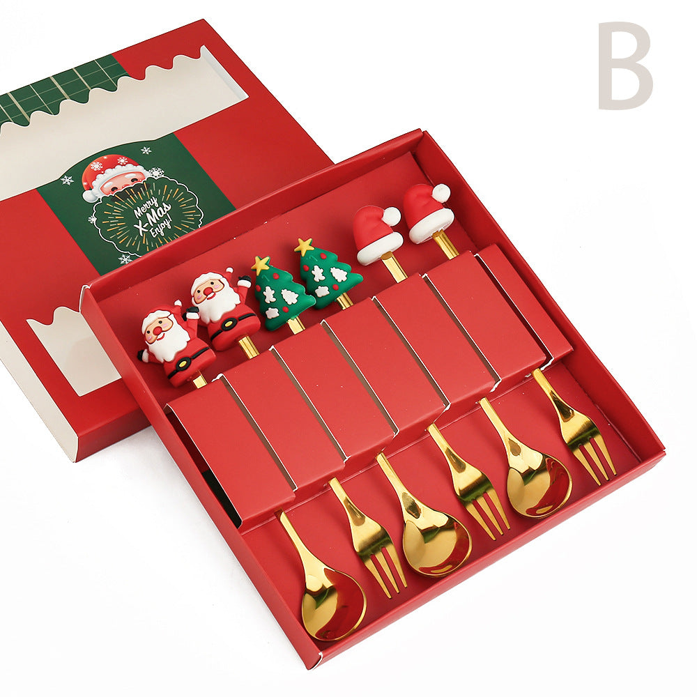 A festive cutlery set with golden forks and spoons in a red box. Handles have Christmas designs: Santa, Christmas trees, and Santa hats. Box lid has "Merry Xmas Enjoy" text.
