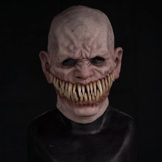 A dark, creepy humanoid figure with pale skin, hollow eyes, and a wide mouth full of sharp, protruding teeth. The background is black, accentuating the eerie appearance.