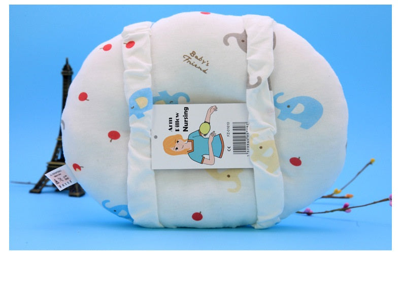 A plush, elephant-patterned baby pillow with a removable cover labeled "Baby's Friend" and "Arm Nursing." It sits against a blue backdrop with an Eiffel Tower miniature nearby.
