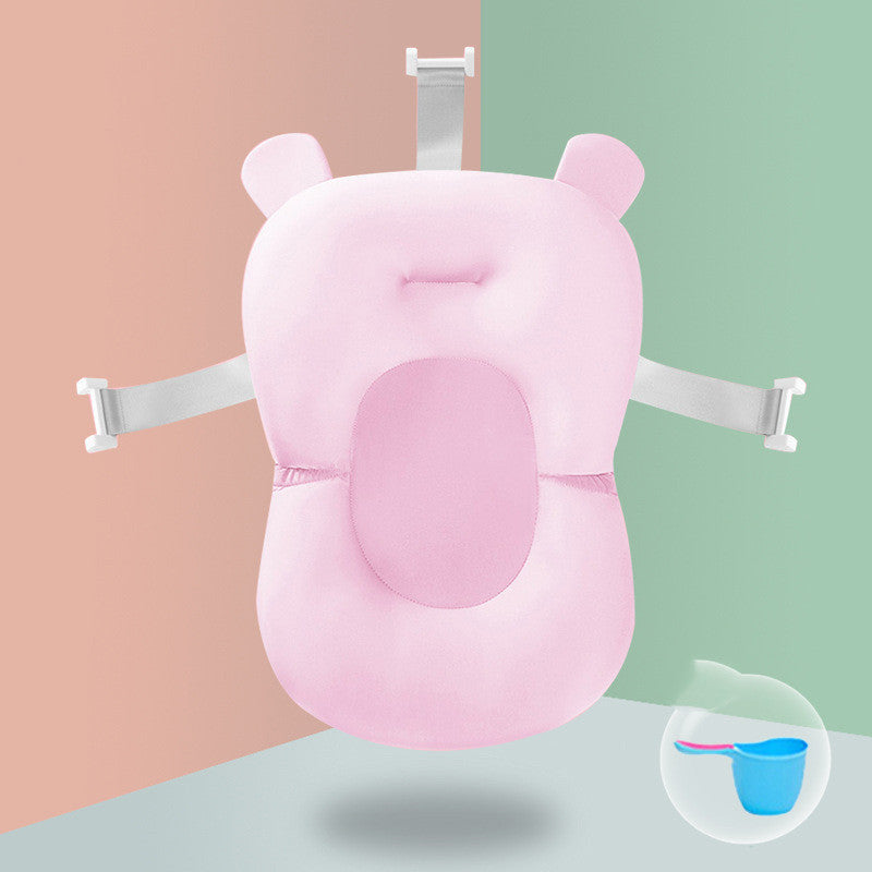 Pink baby bath support cushion with bear ears and white straps. It features a soft, oval center pad for comfort. A small bubble shows a blue water scoop with a pink handle.