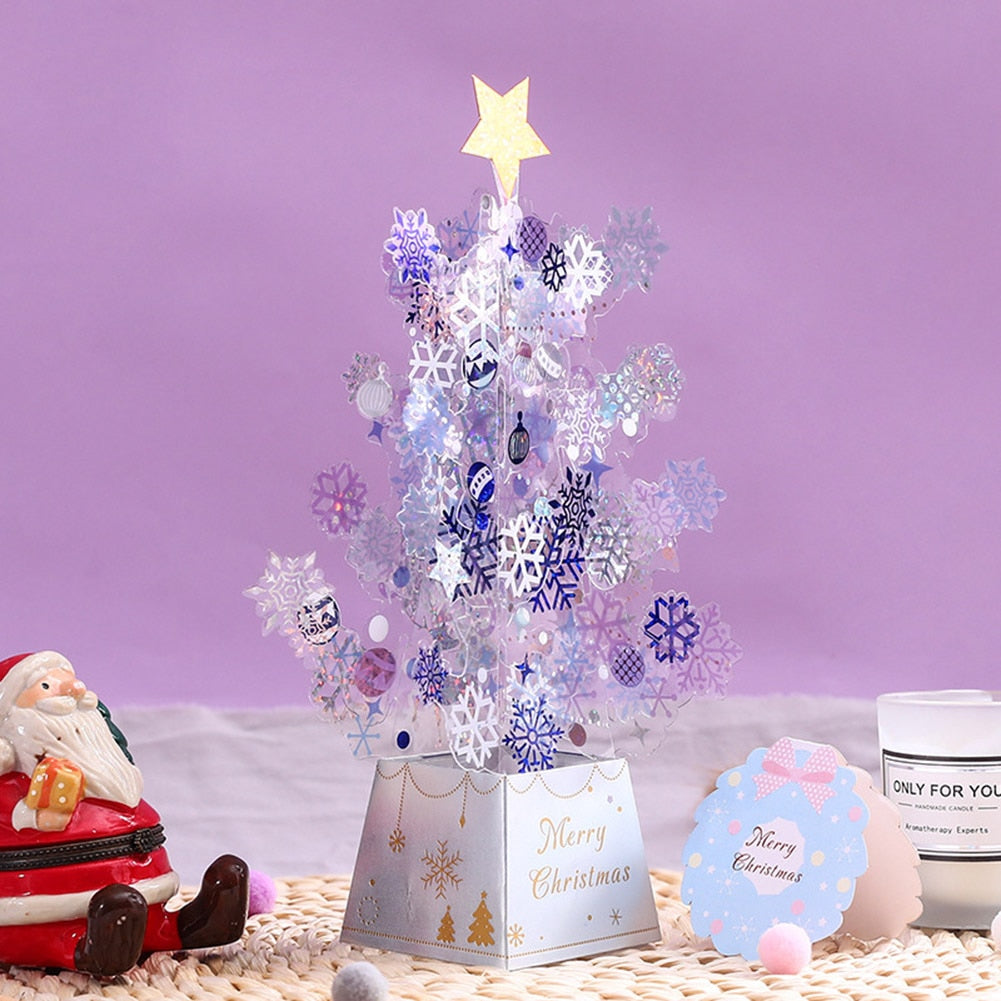 Festive setup with a small decorative Christmas tree adorned with snowflakes, a Santa figurine, and a candle on a woven mat against a purple background.