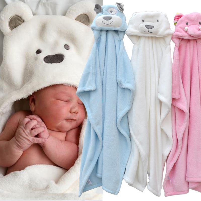 A newborn baby sleeps wrapped in a white, bear-themed hooded blanket next to three soft animal-themed blankets in blue, white, and pink.