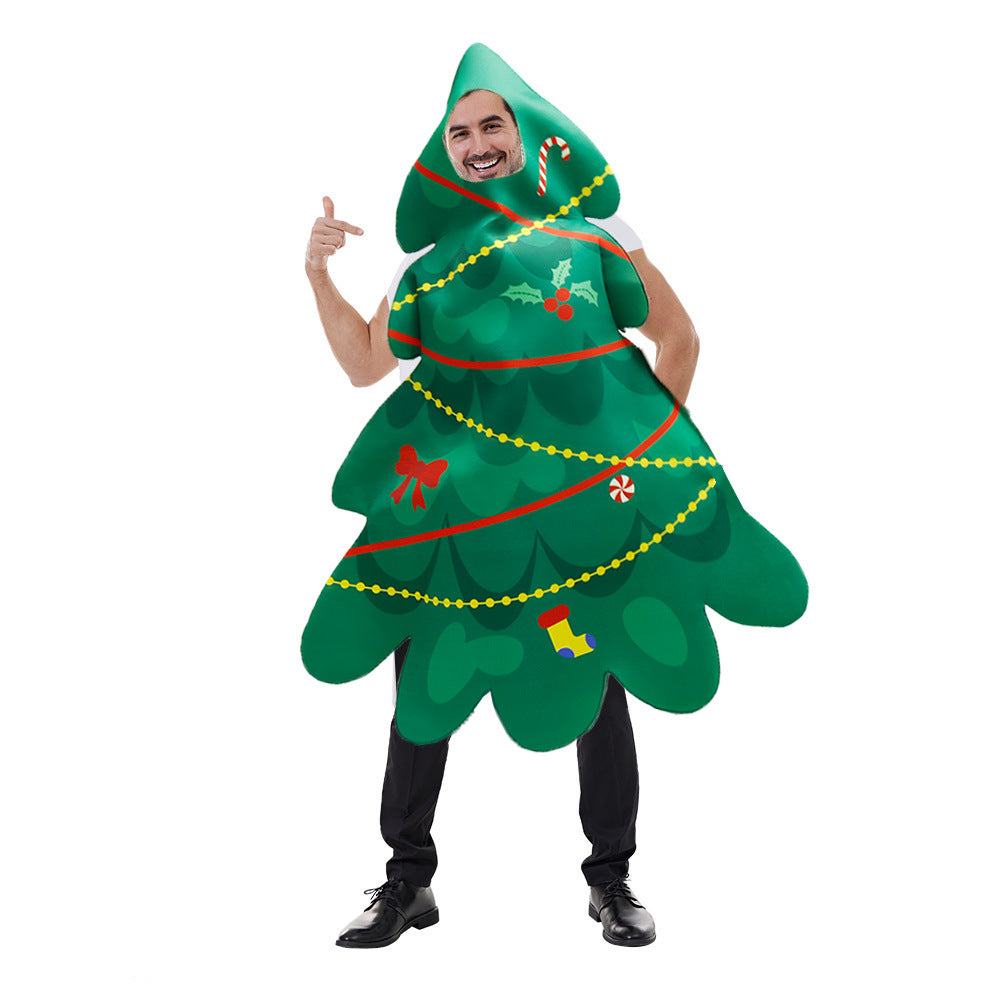 A person in a festive Christmas tree costume, decorated with garlands, bows, a candy cane, and ornaments, smiles while pointing with one hand.