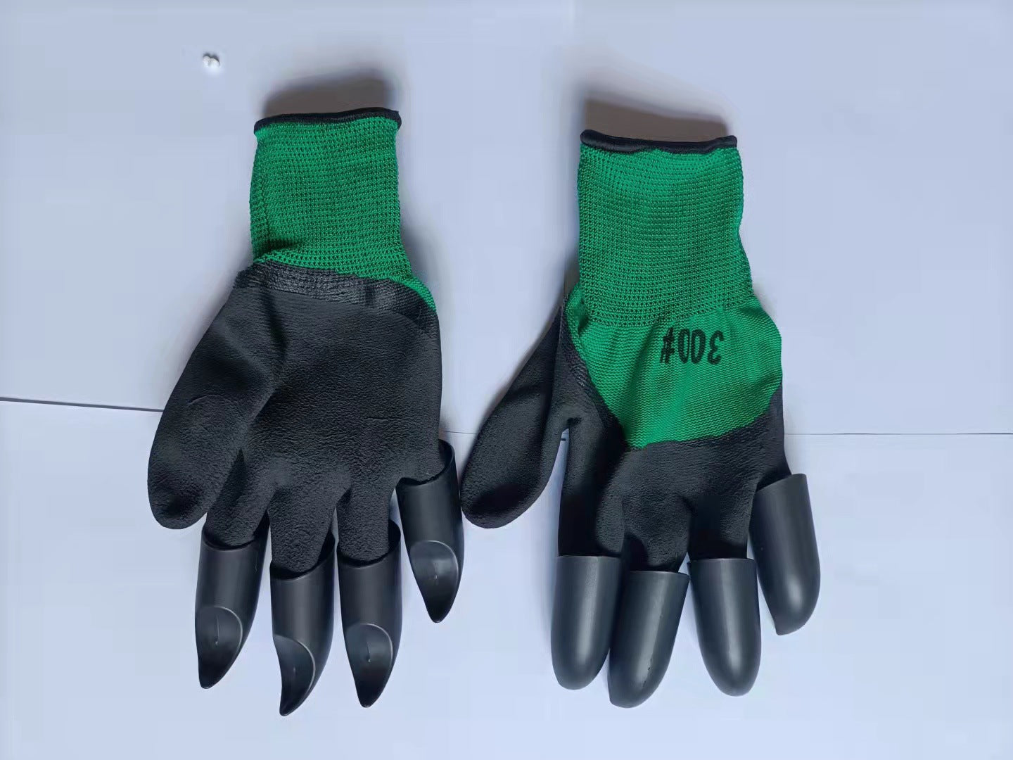 A pair of black rubber gloves with green fabric cuffs, each featuring claw-like tips. The number "300#" is printed on the right glove's fabric.
