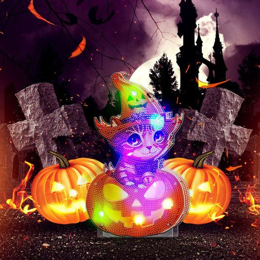 A sparkling cat in a witch hat sits atop a glowing jack-o'-lantern, surrounded by pumpkins and grave markers. A spooky castle and full moon create a Halloween scene in the background.