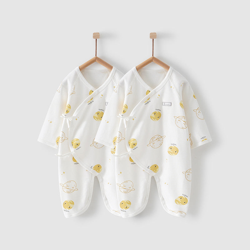 Two white baby kimono-style onesies with yellow planet and smiley face patterns hang on wooden hangers against a plain background.