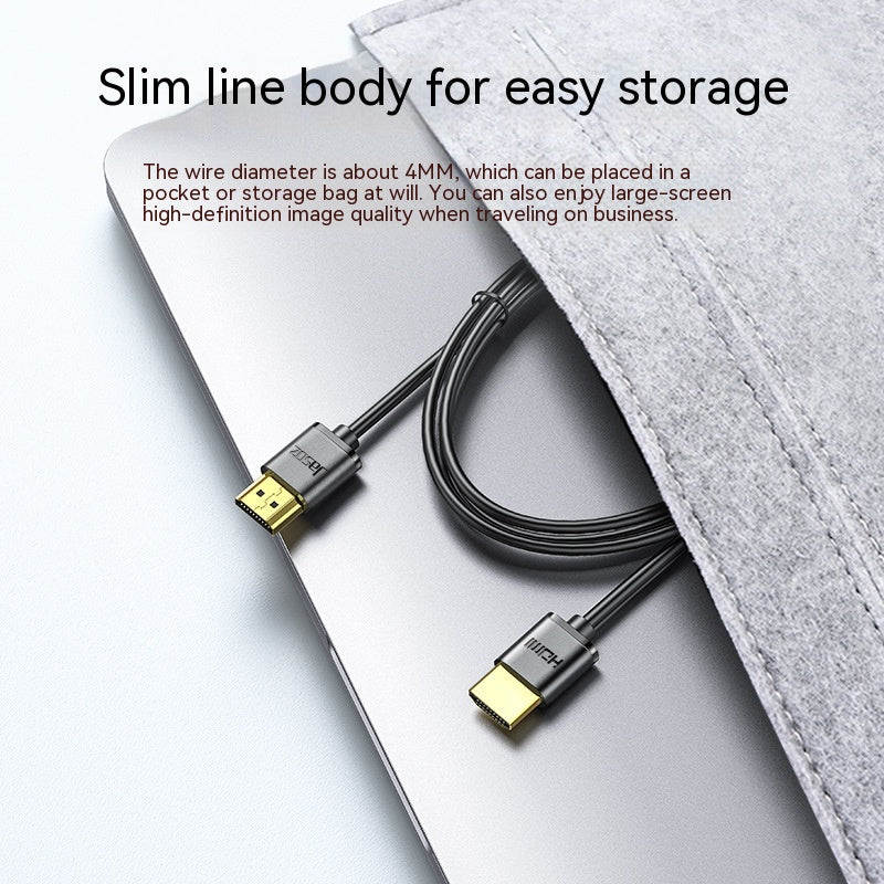 Black HDMI cable with gold connectors on a laptop, partially covered by a gray felt sleeve. Text reads: "Slim line body for easy storage," highlighting its compact design.
