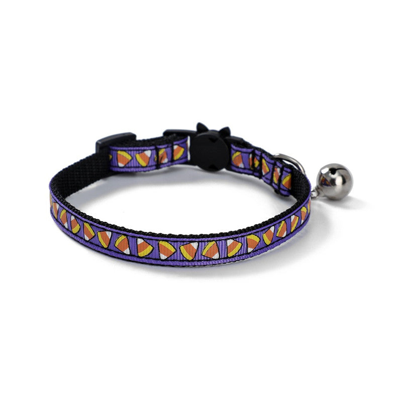 Purple cat collar with candy corn pattern, featuring a black plastic clasp and a small silver bell.