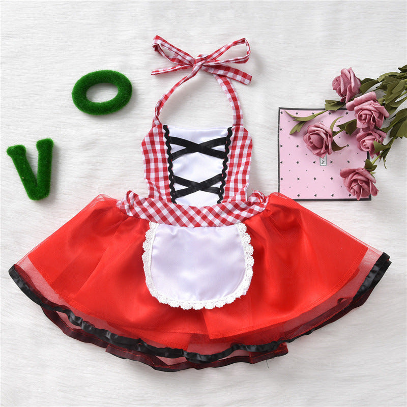 Red and white checkered dress with black lace-up, white apron, and red skirt. Pink roses and a green letter "V" are nearby on a light background.