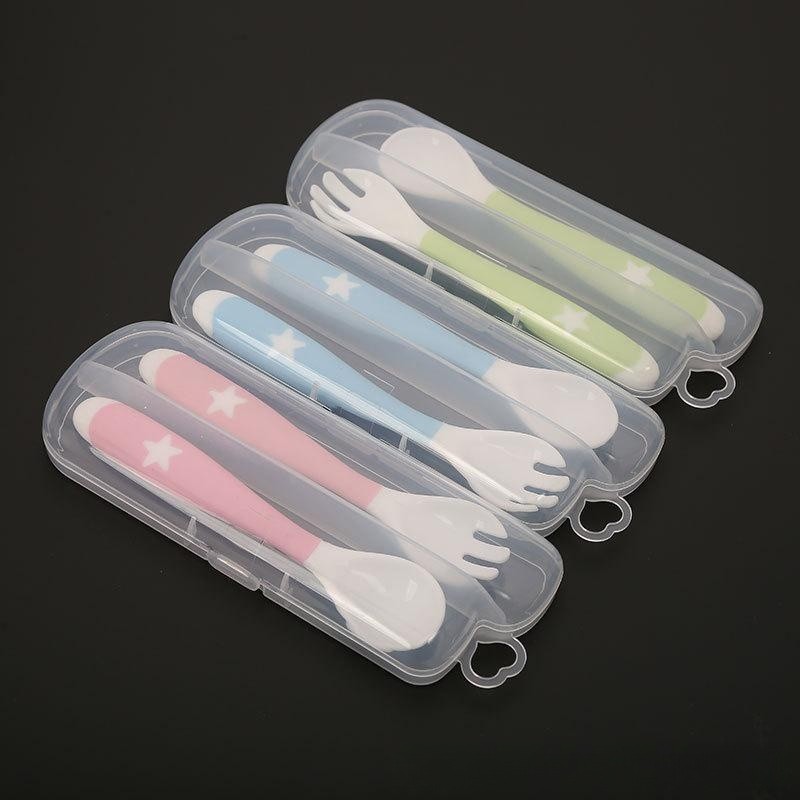 Three sets of baby utensils with forks and spoons in plastic cases. The sets have star patterns and come in pink, blue, and green handles, laid out on a black background.