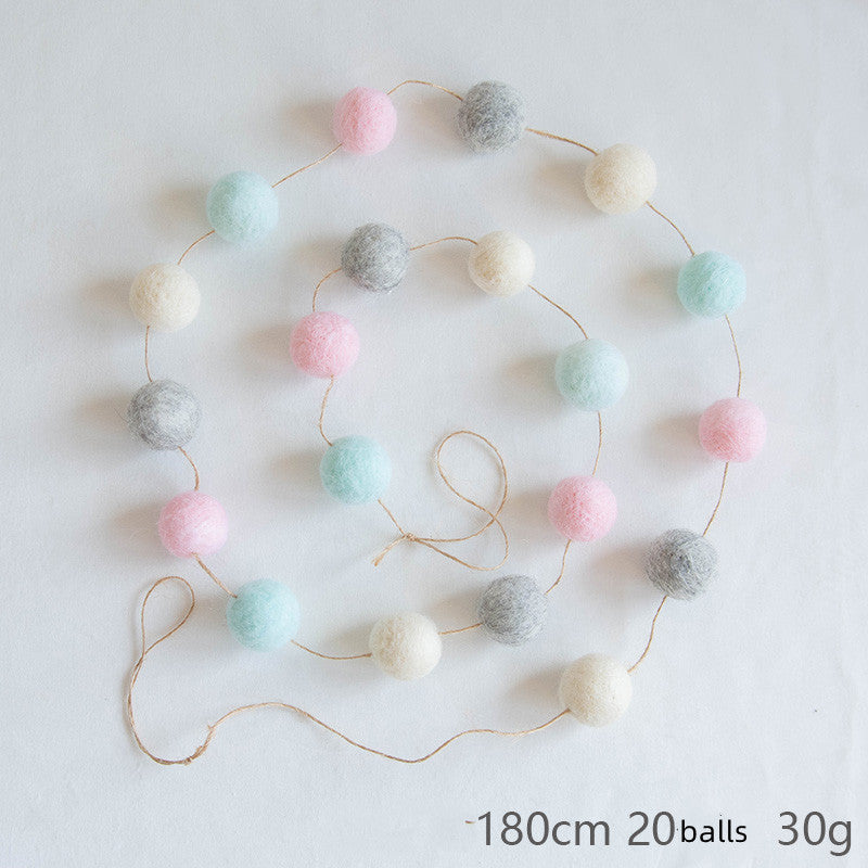 A string of 20 felt balls in pastel colors—pink, blue, white, and gray—connected in a spiral on a light surface. The string measures 180 cm and weighs 30 grams.