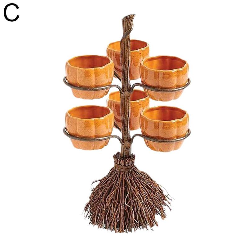 A broom-shaped stand holds six small, orange pumpkin-shaped bowls in two tiers. The base resembles twigs tied together. It's labeled "C" in the top left corner.