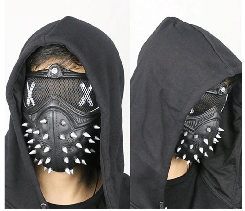 Person wearing a black hooded sweatshirt and a spiked black mask with white "X" designs over the eyes. The mask features a mesh covering and prominent spikes.