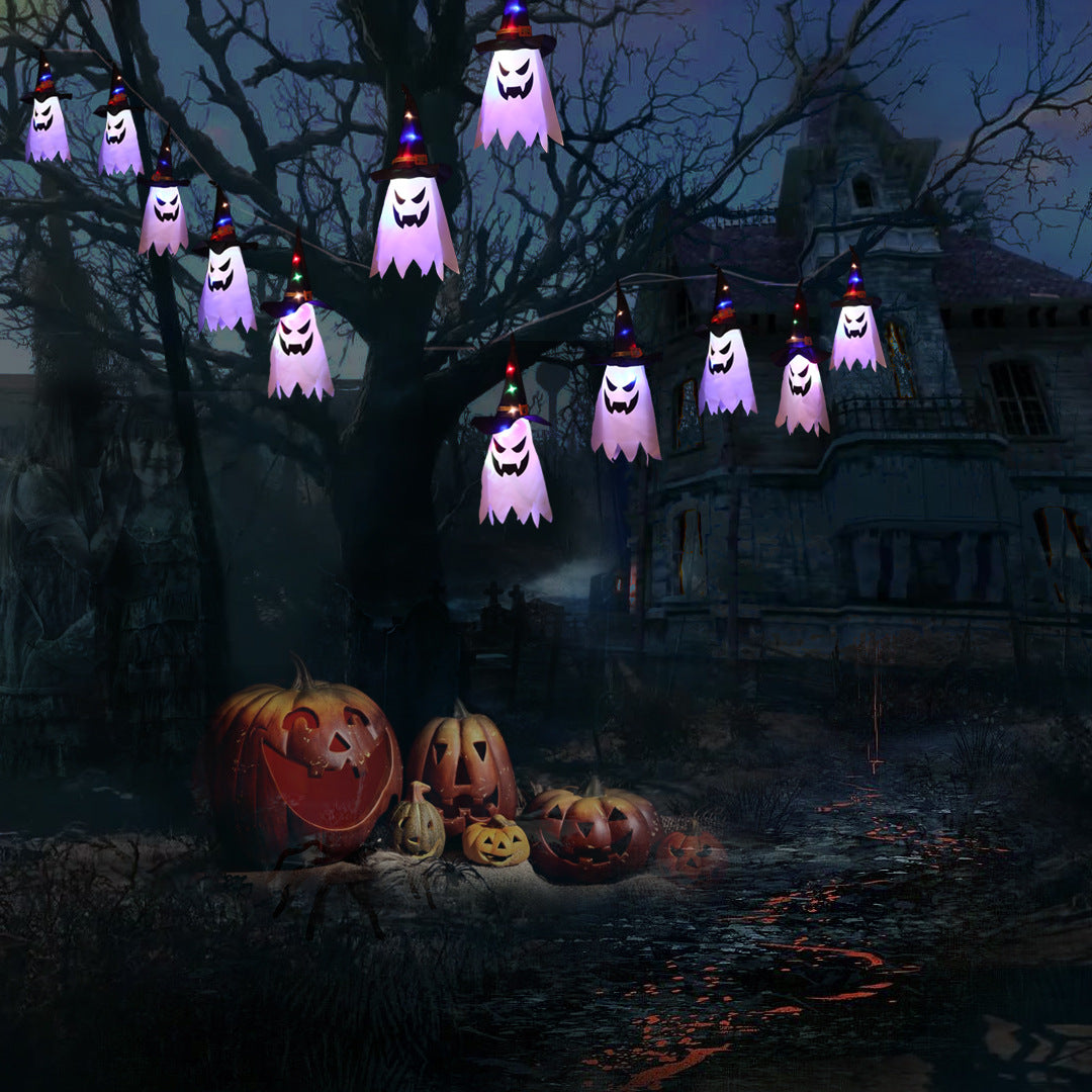Spooky Halloween scene with glowing ghost lights hanging from a tree, a group of carved pumpkins below, and a dark, eerie house in the background.
