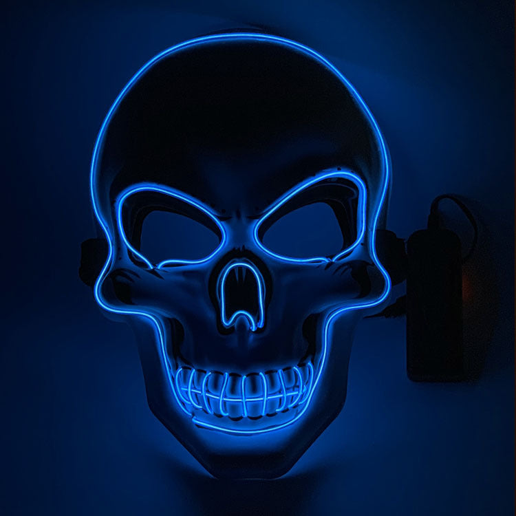Glowing blue skull mask with dark eye sockets, outlined in vibrant neon light against a dark background. The mask features prominent teeth and a small attached power cord.