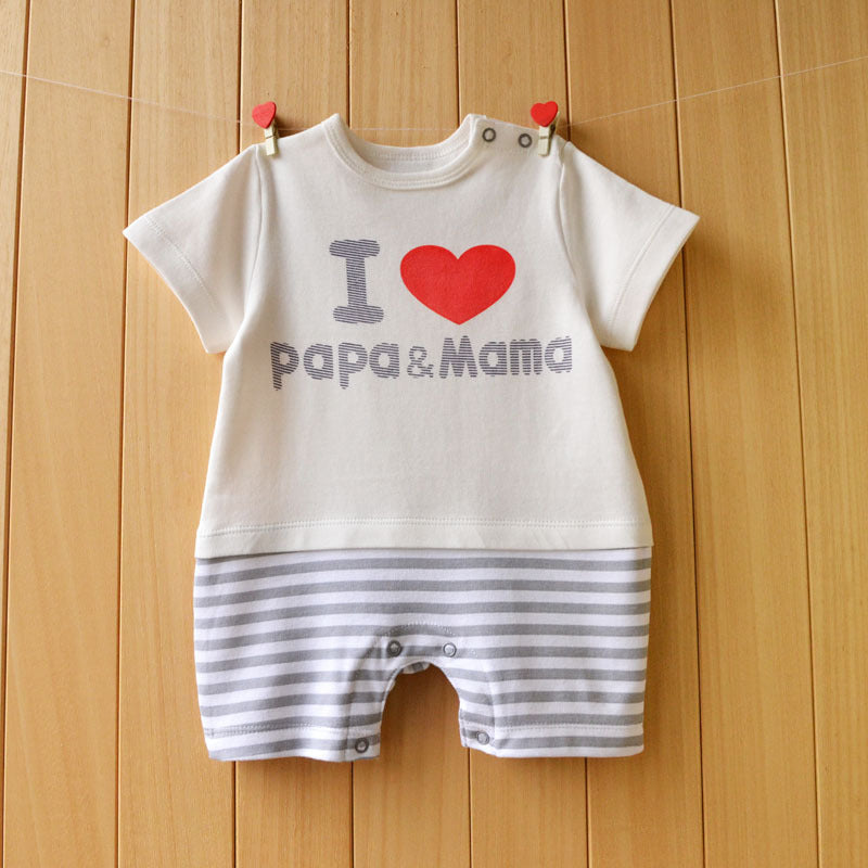 Baby romper with "I ❤️ papa & mama" text, featuring a white top and gray-striped shorts, hanging on a line with red heart-shaped clips against a wooden background.