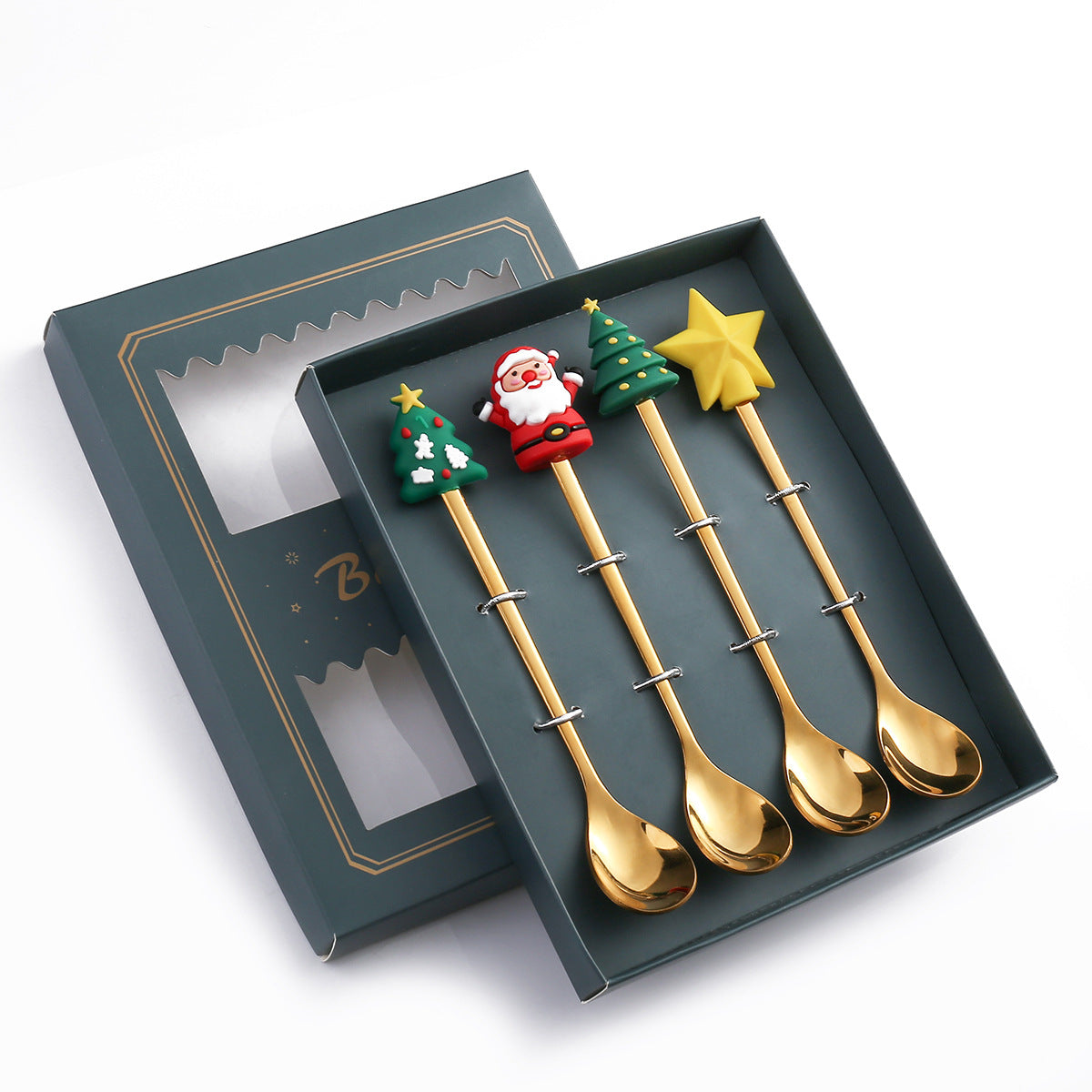 Set of four gold spoons with festive handles: Christmas trees, Santa, and a star. Packaged in an elegant, dark green box with a clear window.