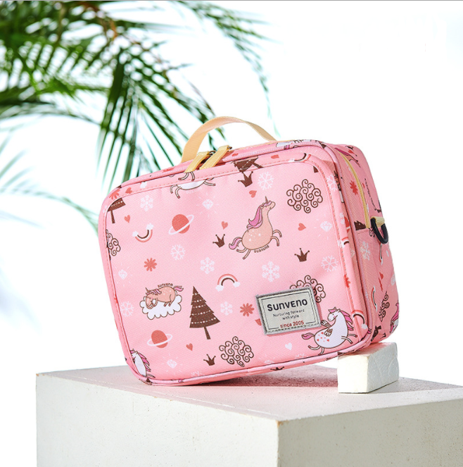 Pink children's bag with unicorn and planet designs, labeled "Sunveno." Features a beige handle, set against a tropical backdrop with green palm leaves.