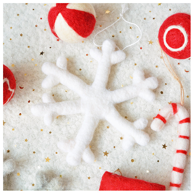 Felt snowflake ornament surrounded by red and white felt ornaments, including a candy cane and balls, on a glittery background with star confetti.