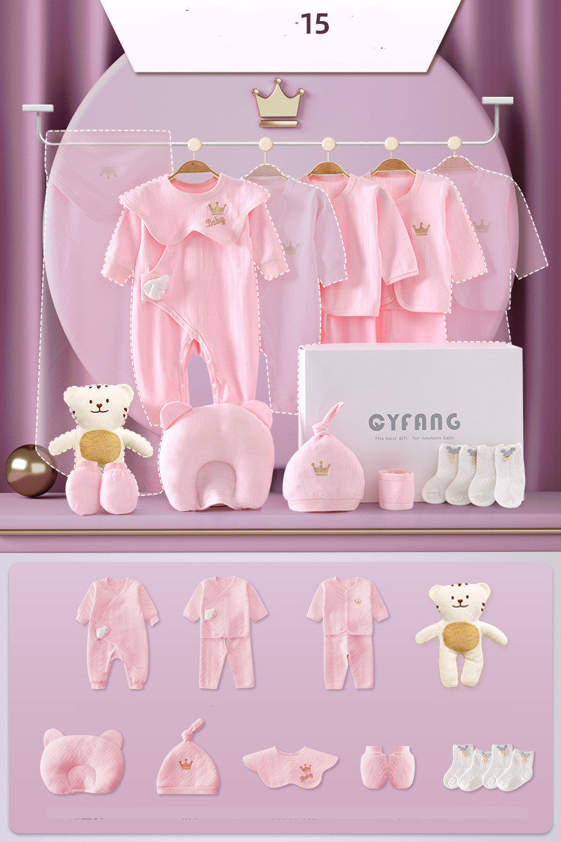 Baby gift set in pink includes onesies, jackets, pants, hat, mittens, socks, bib, bear pillow, and a plush bear, arranged elegantly against a purple draped background.