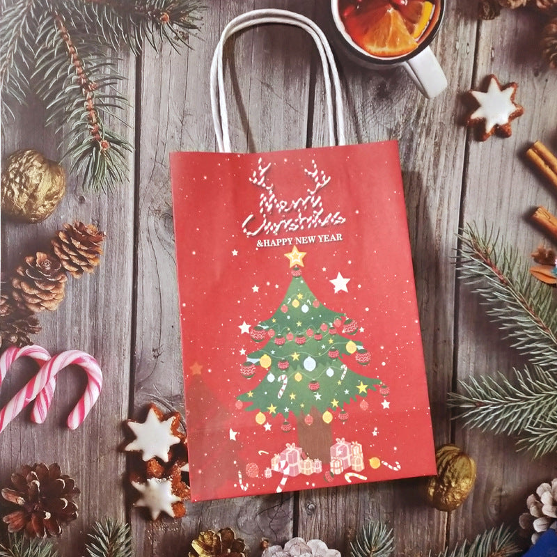 Red gift bag with a Christmas tree design and "Merry Christmas & Happy New Year" text, surrounded by pine branches, candy canes, cookies, and a mug of mulled wine on a wooden surface.