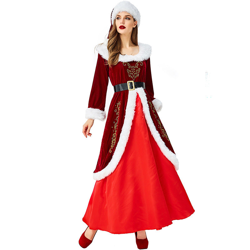 Woman in a festive red Santa dress with white fur trim, black belt, and matching hat. The dress features gold embroidery and a full red skirt. She wears red shoes.