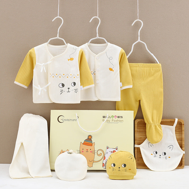 Baby clothing set with cat designs, including yellow and white jackets, pants, hat, bib, and towel. Displayed on hangers and a brown board, with a decorative gift bag.
