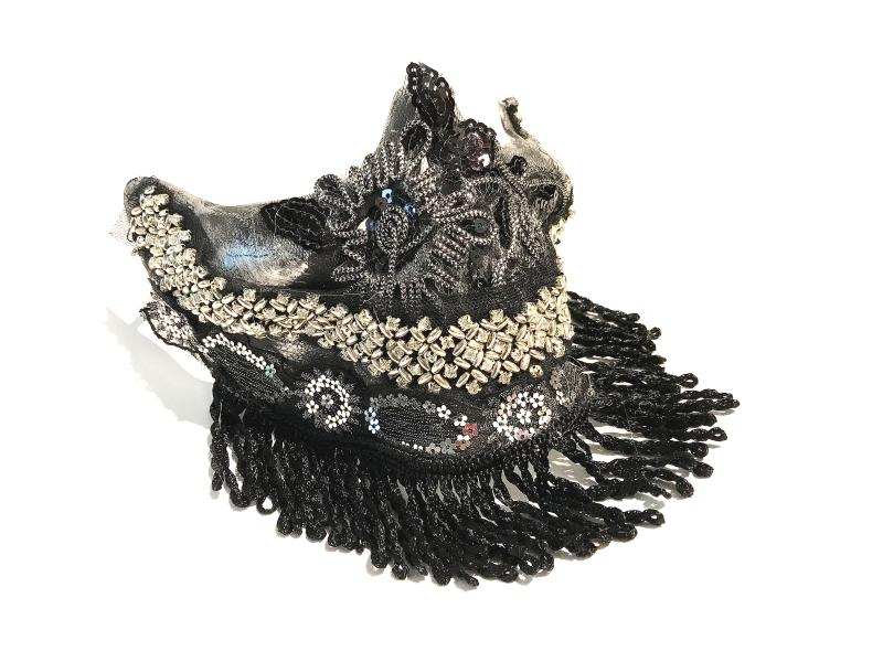 Intricate black and silver beaded mask with ornate floral designs and fringe detailing. The mask features layered beads and shimmering accents on a white background.