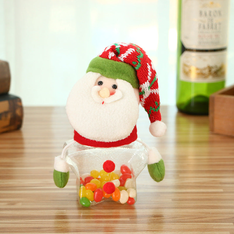 A plush Santa head with a red and green hat tops a star-shaped glass container filled with colorful jelly beans, set on a wooden table. 