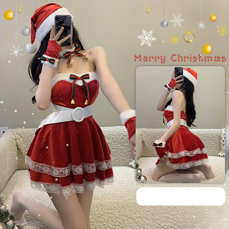 Person wearing a festive Santa-themed dress with a red and white color scheme, adorned with lace and bells. They are posing indoors with Christmas decorations.