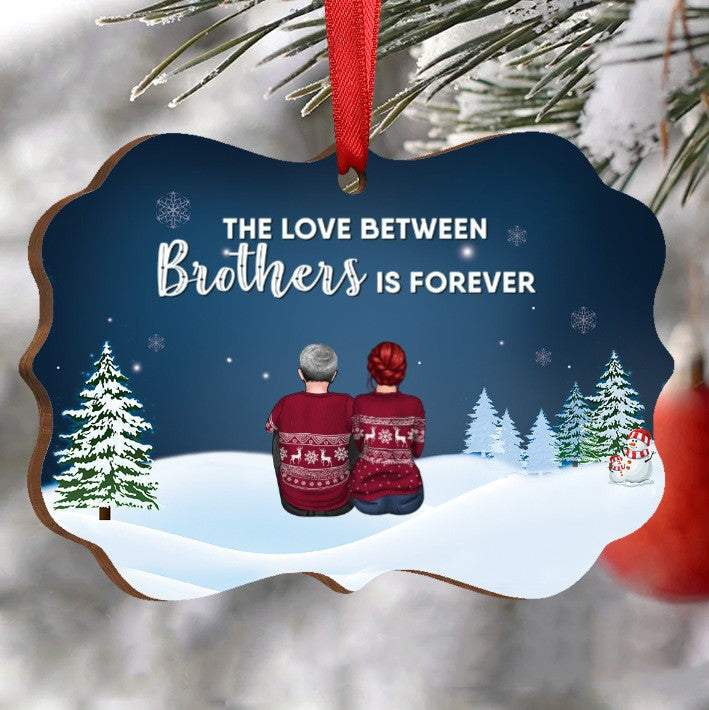 A Christmas ornament features two figures in festive sweaters sitting on snow. Text reads "The love between brothers is forever" surrounded by snowflakes and trees.