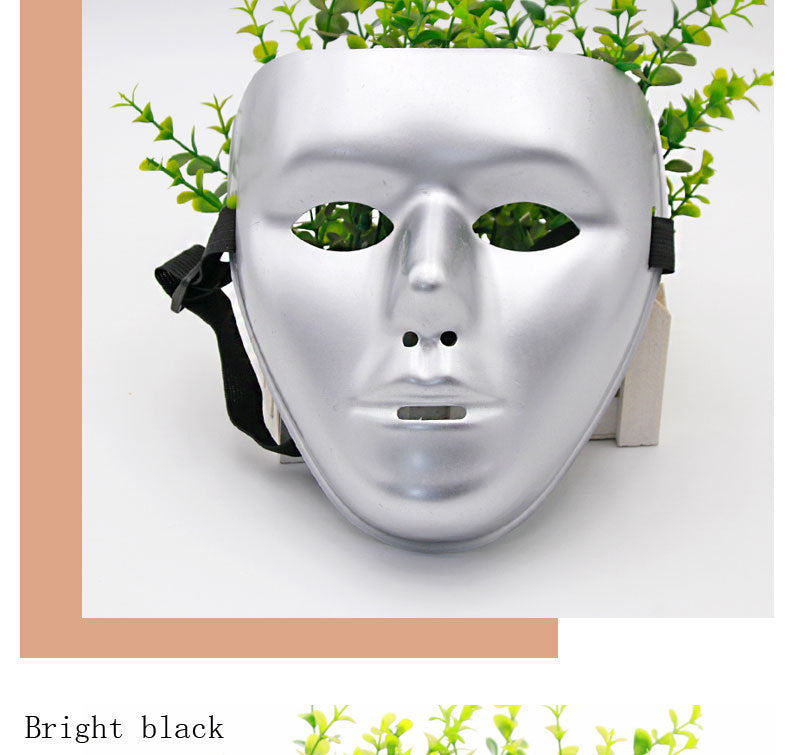 A silver face mask with black straps, resting against a background featuring green plant leaves peeking through. The text "Bright black" is written at the bottom.