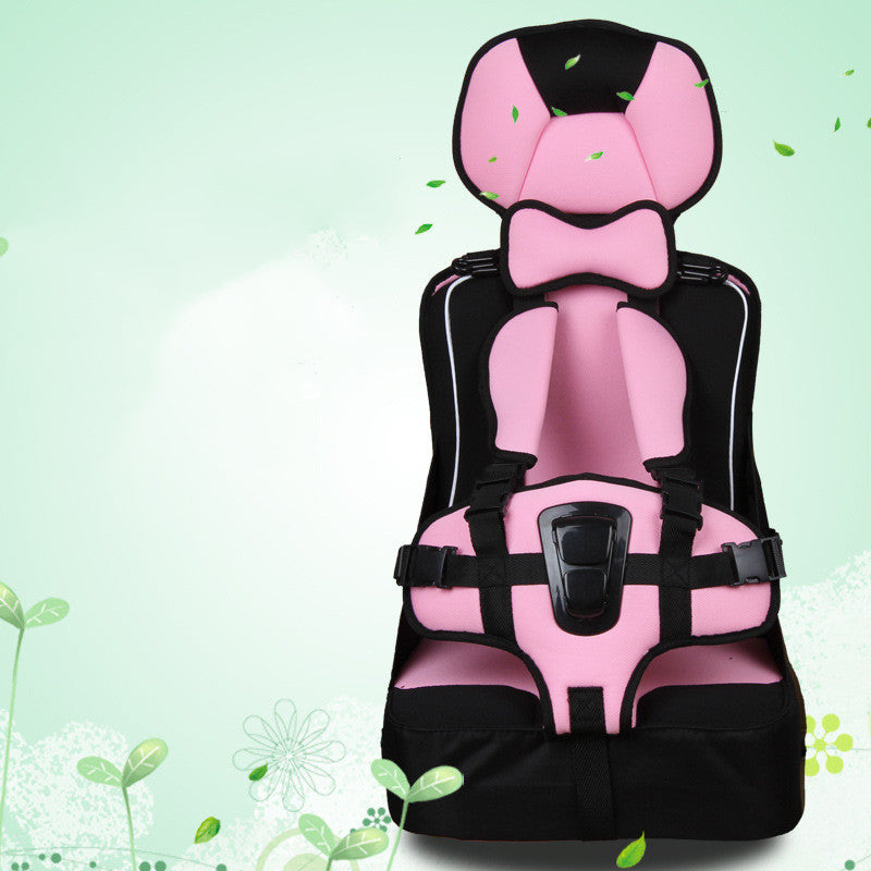 Pink and black child car seat with safety harness, set against a light green background decorated with small green leaves and floral designs.