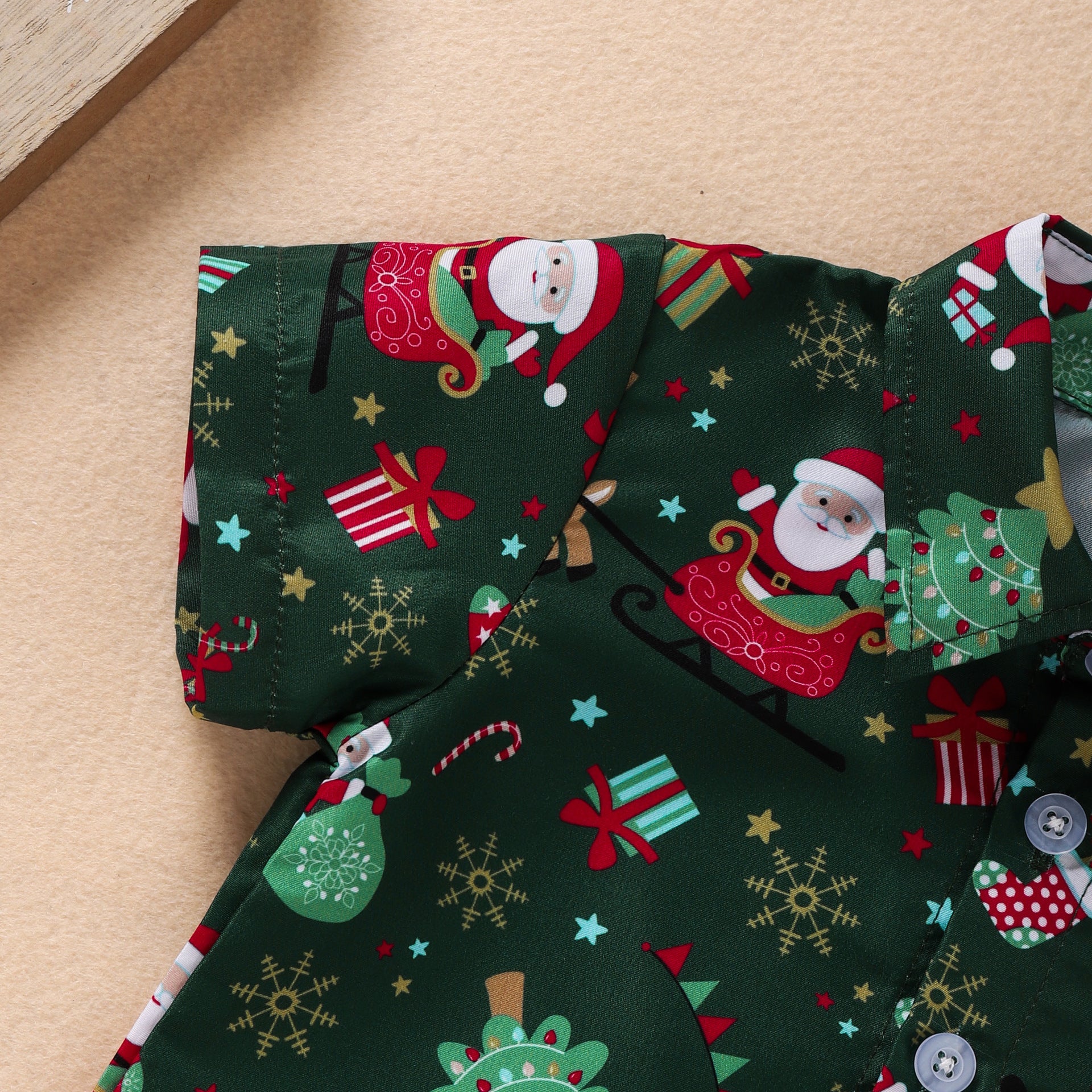 Close-up of a green shirt with a festive Christmas print featuring Santa Claus in a sleigh, presents, snowflakes, candy canes, and Christmas trees.