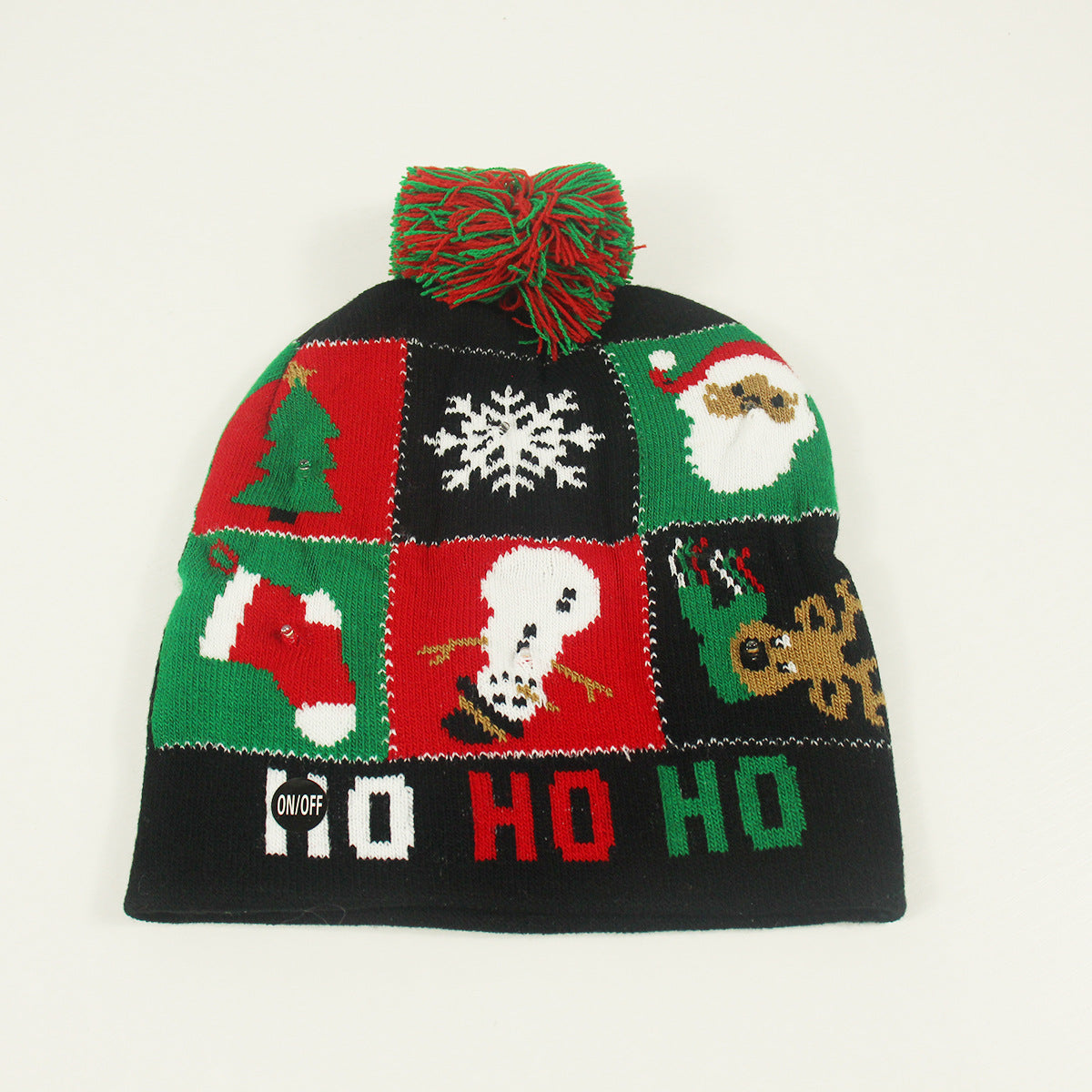 Knitted Christmas hat with red and green squares featuring festive designs: tree, snowflake, Santa, stocking, snowman, lights, and gingerbread man. Topped with a red-green pom-pom.