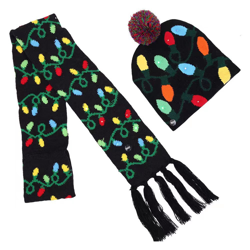 Black winter hat and scarf set decorated with colorful Christmas lights pattern. The hat features a multicolored pom-pom, and the scarf has fringe at the ends.