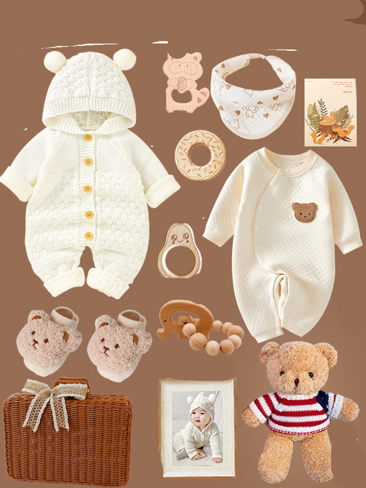 Baby items on a brown background, including a bear outfit, onesie, plush bear slippers, teething toys, bib, teddy bear, wicker basket, and a framed photo of a baby in a bear costume.