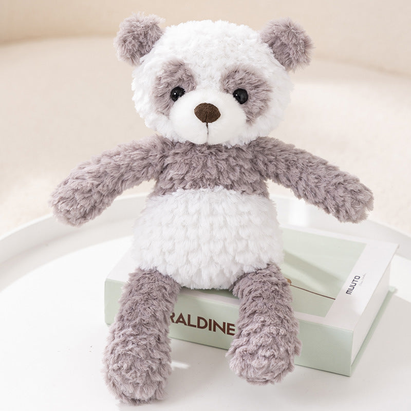 A fluffy plush teddy bear with white and gray fur sits on a closed book on a white surface, looking forward with a cute expression.
