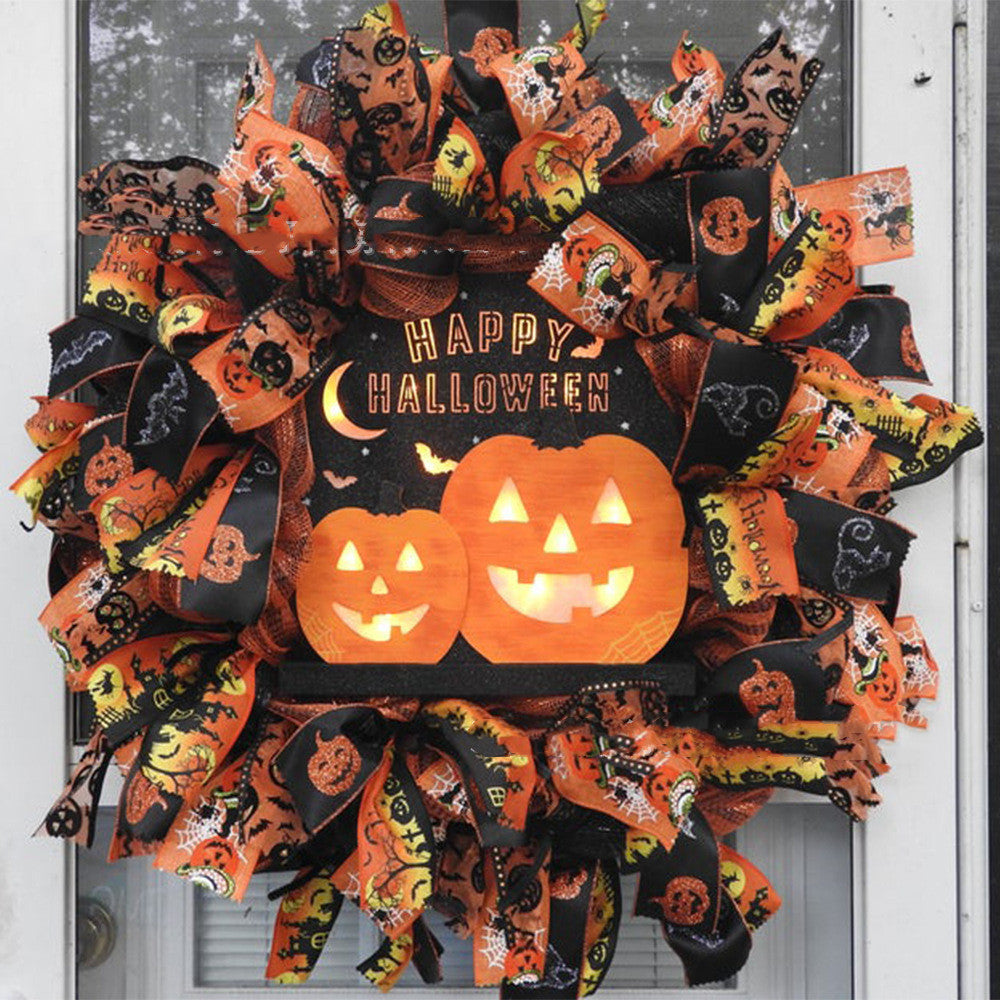Festive Halloween wreath with glowing pumpkin faces and "Happy Halloween" text, surrounded by orange and black ribbons featuring spider webs and spooky designs.
