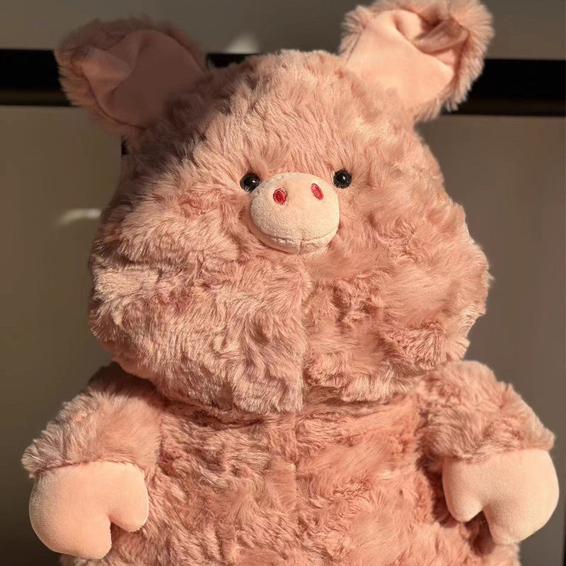 A fuzzy, beige plush toy resembling a pig, with pink snout and ears, black button eyes, and a textured fur surface, standing against a neutral background.