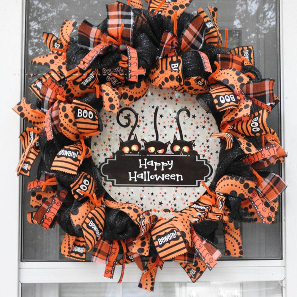 A Halloween wreath with orange and black ribbons, featuring "BOO" and "Beware!" text. In the center, a plaque with “Happy Halloween” and three black cats on a starry background.