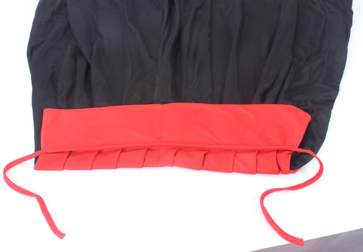 Black garment with a ruched design and red waistband, featuring pleated red fabric and tie straps at the bottom.