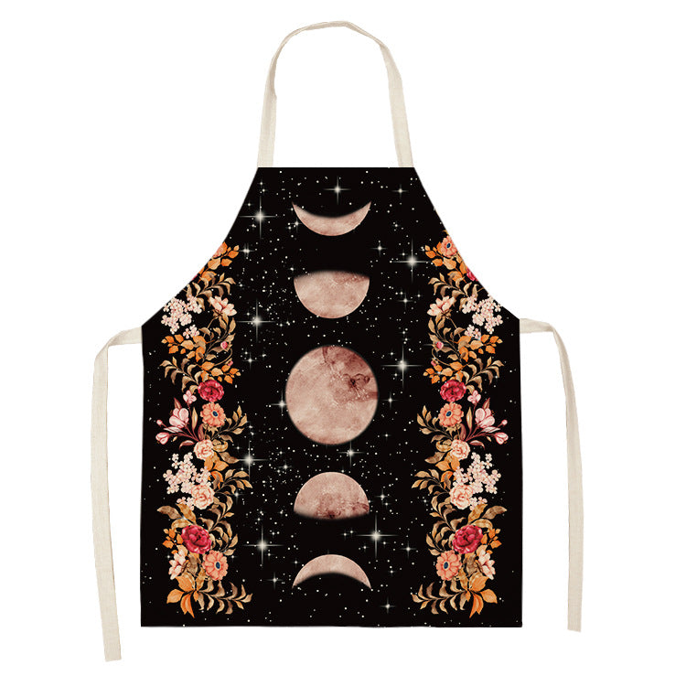 Black apron with moon phases in the center, surrounded by floral patterns featuring pink and orange flowers on a starry background.