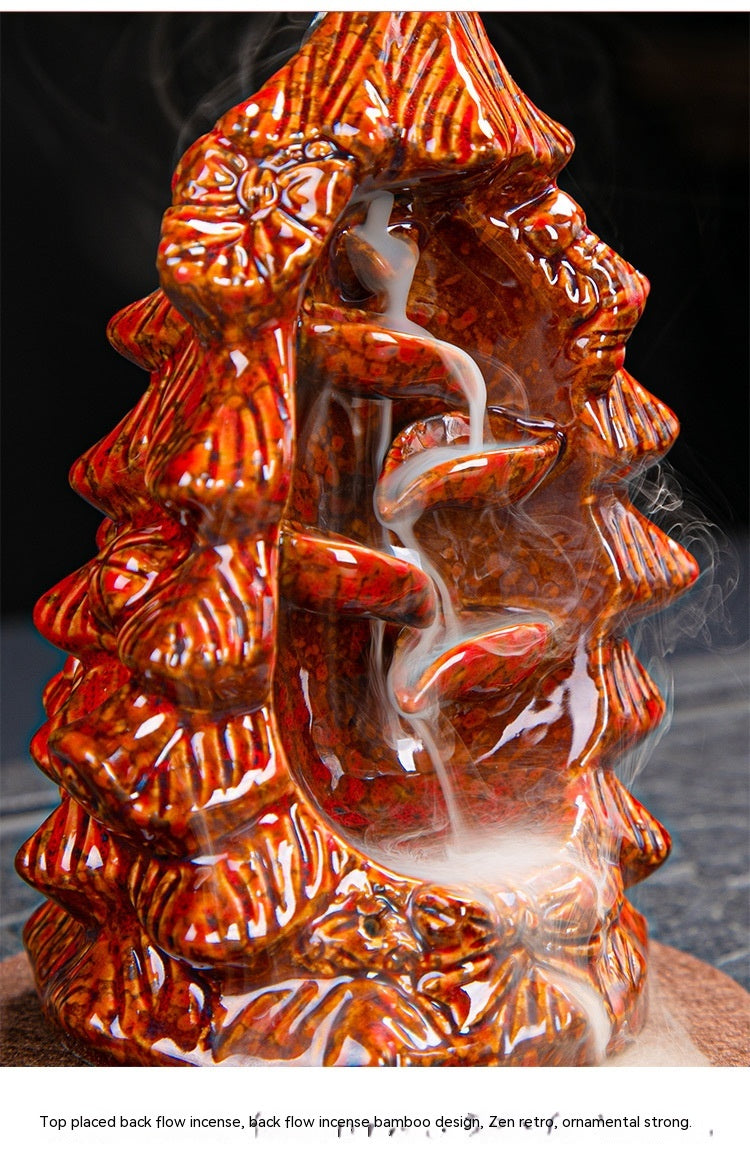 Red ceramic backflow incense holder with a bamboo design. Smoke cascades down a series of curved, decorative paths, creating a calming, zen-like effect.