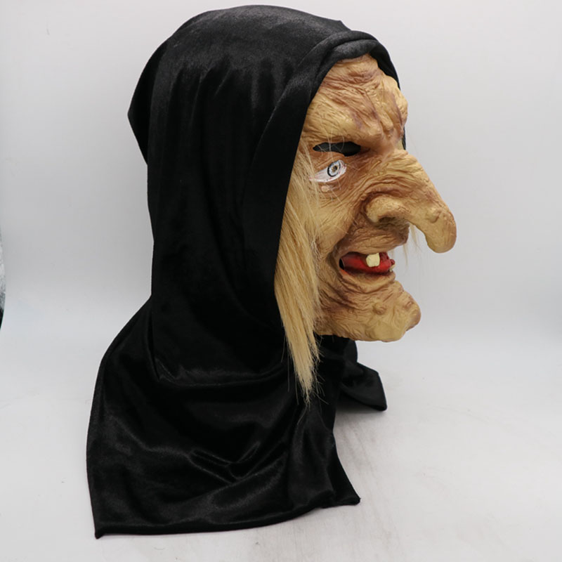 A witch mask with a long nose, yellowed teeth, and wrinkled skin, wearing a black hood. The mask has exaggerated facial features and stringy blonde hair.