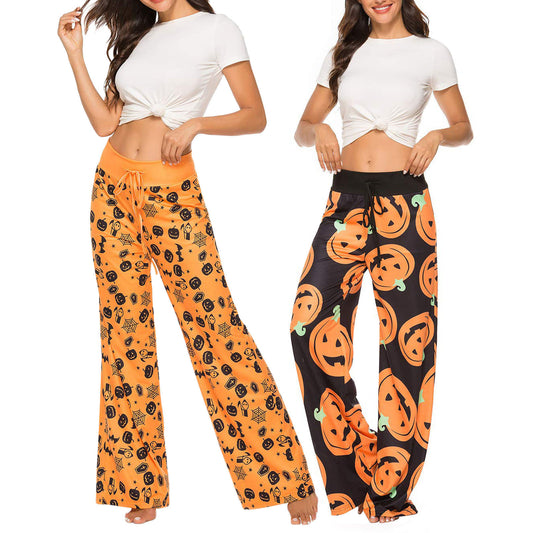 Two women in white tops and Halloween-themed pajama pants; one pair features black holiday icons on orange, the other has orange jack-o'-lanterns on black.