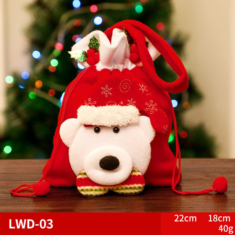 A festive red drawstring bag with a plush bear face wearing a Santa hat and a striped scarf, set against a blurred Christmas tree background with colorful lights.